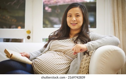 This Book Is A Must-read For Any Expecting Mom. Portrait Of A Pregnant Woman Reading A Book At Home.