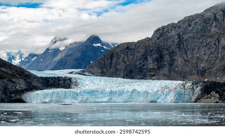 This breathtaking image captures a massive glacier surrounded by rocky mountains, epitomizing the grandeur of nature and the beauty of glacier formations.