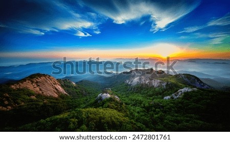 This breathtaking image captures the stunning beauty of a mountainous landscape at sunset. The sky is painted with vibrant colors ranging from deep blues to fiery oranges.