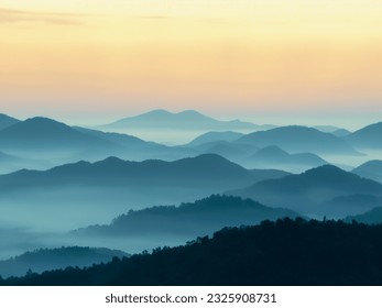 This breathtaking photograph transports the viewer to a realm where mountains and mist converge in an exquisite dance. The mist delicately embraces the majestic peaks, creating an atmosphere of charm.