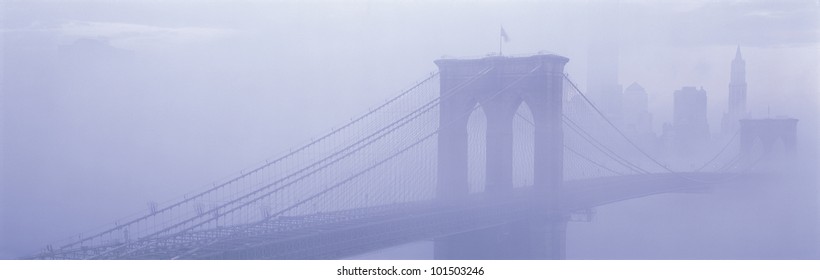 This is the Brooklyn Bridge over the East River. There is a morning fog enveloping the bridge and city. - Powered by Shutterstock