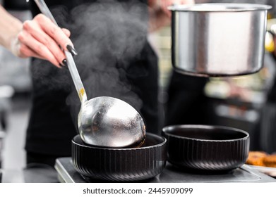 In this bustling kitchen, a chef pours steaming soup into a black bowl, capturing the essence of culinary activity. atmosphere is filled with heat and movement, emphasizing professional environment - Powered by Shutterstock