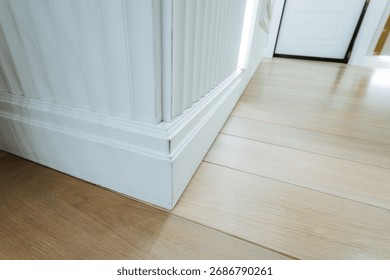 This captivating closeup view showcases a sleek baseboard with smooth wooden flooring in a modern setting, highlighting elegant design features that enhance home decor and add sophistication