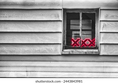 This captivating image portrays a window set within a weathered wooden wall. The monochromatic exterior, composed of horizontal grey slats, contrasts sharply with the vibrant neon glow of a 
