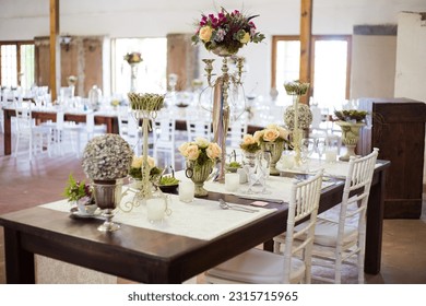 This captivating image showcases the elegant decor and stunning floral arrangements of a real wedding. The photograph features a beautifully decorated table in a charming wedding venue.
