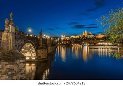 This captivating nighttime photograph of Prague showcases the iconic Charles Bridge and the stunning Prague Castle illuminated against the deep blue twilight sky. - Powered by Shutterstock