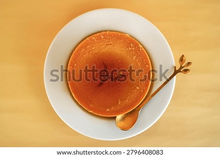 This is a caramel pudding placed on a white plate with a gold spoon beside it.