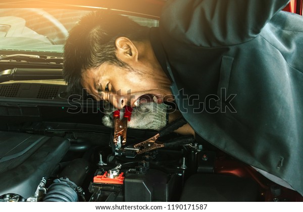 This career inspection asian man\
car service charging battery car on\
blurry\
background.\
