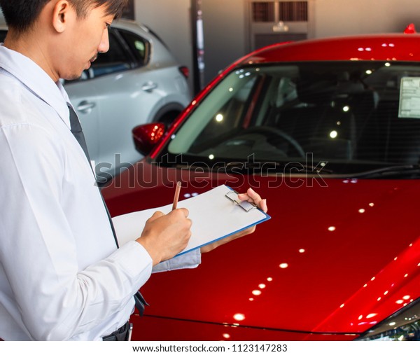 This career man saleman business\
inspection writing on notepad or book, paper with car blurry\
background.for transport automobile automotive\
image.