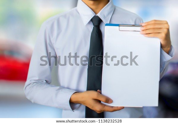 This career man saleman\
business inspection writing note on notepad or\book, paper with\
showroom  blurry background.for transport automobile\automotive\
image.