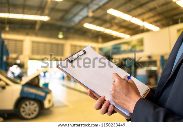 This career man saleman\
business inspection writing note on notepad or \book, paper with\
car service blurred background.for transport automobile\
\automotive image.