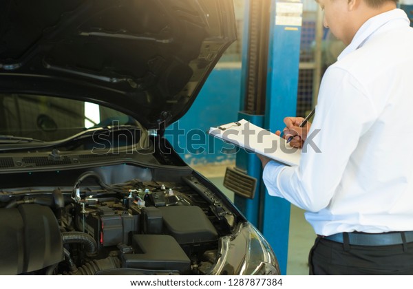 This career man saleman business\
inspection writing note on notepad or book, paper with car blurry\
background.for transport automobile automotive\
image
