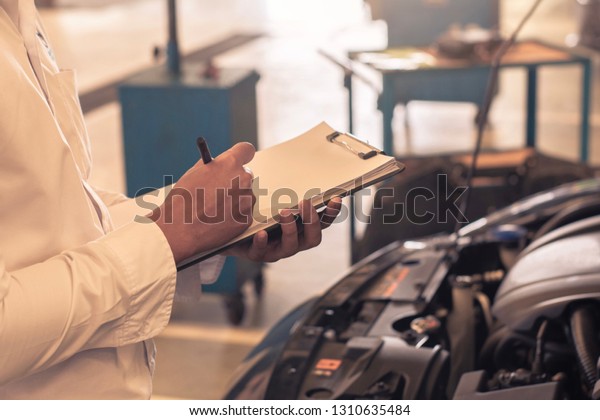 This career man saleman business\
inspection writing note on notepad or book, paper with car blurry\
background.for transport automobile automotive\
image.