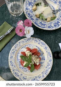 This charming table setting invites you to savor every bite. Caprese salad, Caesar, wine — timeless elegance.