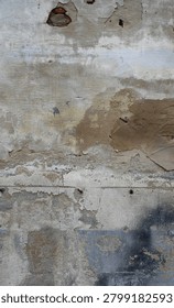 This is a close up of a deteriorating concrete wall surface with worn cement layers, weatherworn paint, and exposed red brick areas. The rough, porous surface includes a terra cotta patch, blue paint remnants, black overspray, and multiple holes.