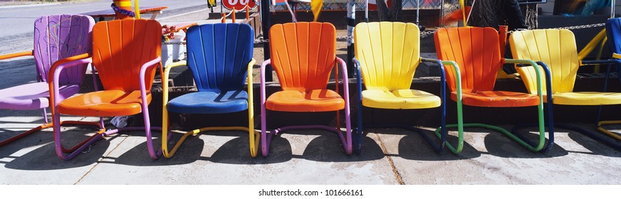 This Is A Close Up Of Multi-colored Metal Lawn Chairs. They Are Located Outdoors On Route 66.