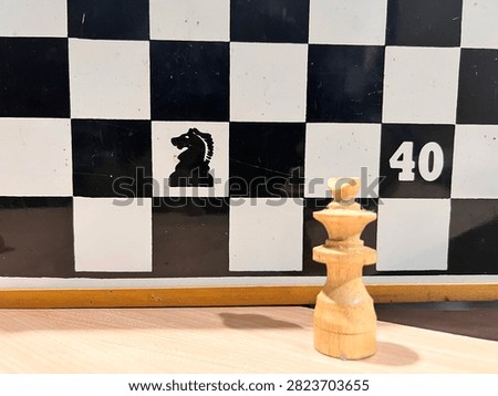 This is a close-up, low-angle shot of a set of light-colored wooden chess pieces lined up on a wooden surface.

In the foreground, the are in sharp focus - you can see the natural wood grain and signs of wear and age. Some chipped and damaged, most noticeably the knight piece in the center which has a broken nose and a large chip on its side. The tallest pieces, the king and queen, stand in the middle of the row, flanked by pawns and other pieces.