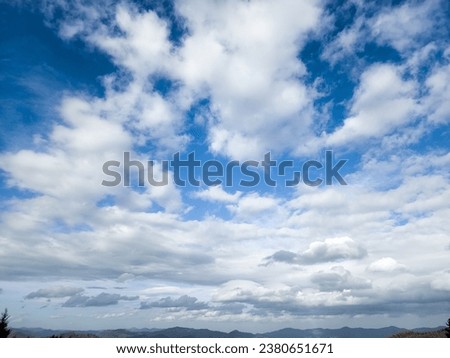 In this close-up photo, cumulus and stratus clouds dance across the sky, their shapes intricate and distinct. Cotton tufts of cumulus clouds intertwine with stratus, smooth expanses of stratus clouds