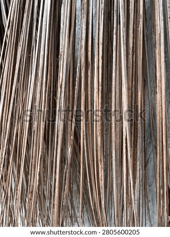 This is a close-up photograph of the thin, dry, and fibrous sticks of a traditional coconut leaf broom