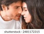 This is a close-up portrait of a man and a woman about to kiss. They are looking into each others eyes and appear to be in love.