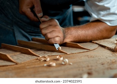 This close-up shows a guitar luthier using a chisel to shave the bracing of an acoustic guitar. The luthier is carefully working to ensure that the braces are the correct shape and size.