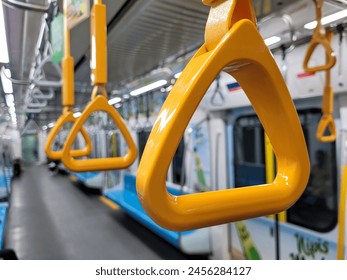 This is a close-up view of multiple yellow passenger handles located inside the carriage of an MRT train.