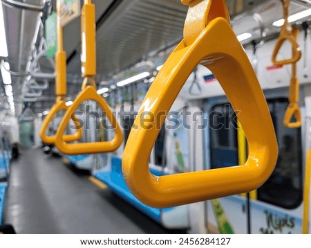 This is a close-up view of multiple yellow passenger handles located inside the carriage of an MRT train.