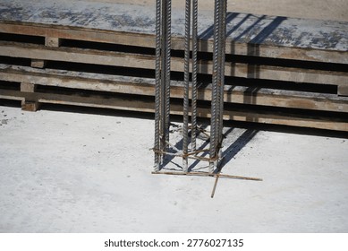 This close-up view shows the base of a steel rebar column emerging from a freshly poured concrete slab on a sunny construction site, highlighting foundational work.