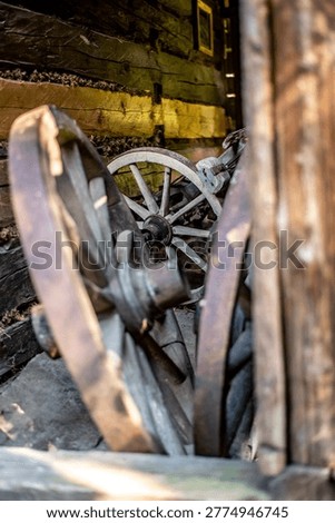 This comprehensive collection of high-quality documentary photographs captures the authentic atmosphere of historical rural life within the Wallachian Open Air Museum in Roznov pod Radhostem, Czech Republic. The images offer a detailed look into the interior of a traditional timber-framed barn and workshop, showcasing an extensive array of antique agricultural machinery and handcrafted wooden tools used by ancestors in the Moravian Wallachia region.The focus lies on the intricate craftsmanship of vintage wooden horse-drawn wagons, carts, and carriages, featuring weathered spoked wheels, iron-forged reinforcements, and hand-woven wicker baskets used for transporting goods. Each frame highlights the rustic texture of aged wood, the patina of time-worn metal components, and the dusty, atmospheric lighting of the museum's interior. Notable details include a heavy wooden mallet, disassembled wheel parts, and various farming implements stored in a dimly lit, hay-filled environment. These photographs serve as a visual archive of European folk architecture, traditional carpentry, and the pre-industrial era of farming, reflecting the hard-working spirit and ingenuity of 19th-century rural society. The composition emphasizes the play of light and shadow on organic materials, making it ideal for historical documentaries, educational materials, and heritage preservation projects.