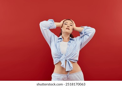 This confident young woman showcases her beauty with bright makeup while posing dramatically on red. - Powered by Shutterstock