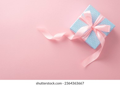 This congratulatory scene showcases top view of a pastel blue gift box adorned with polka dots and an adorable pink ribbon bow, all set on a pastel pink backdrop Foto Stock