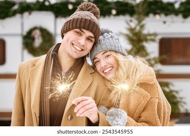 This cozy winter moment features a smiling couple holding sparklers amid a snowy landscape. They are dressed warmly, enjoying each other's company and the festive atmosphere. - Powered by Shutterstock