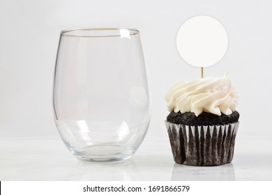 This Cupcake Topper And No Stem Wine Glass Mock Up Features An Elegant Stemless Wineglass Resting Next To A Tempting Chocolate Cupcake.