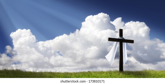 This dramatic Easter Morning Sunrise panorama with blue sky, bright clouds, sunbeams, and large cross on a grass covered hill makes a great banner cover for print or web.