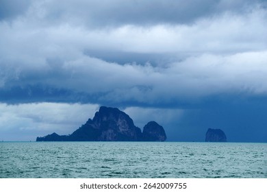 This dramatic seascape features dark clouds hanging over tranquil waters, with majestic islands emerging in the distance, evoking a sense of wonder and adventure.