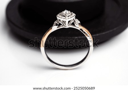 This elegant diamond ring features a square-shaped centerpiece with a double halo of diamonds, set in a mix of silver and rose gold tones. The dark background enhances the brilliance of the stones