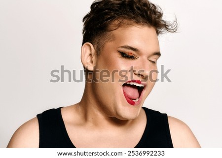 This engaging portrait features a queer individual expressing happiness with creative makeup.
