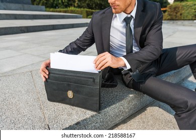 This is exactly what I need. Close-up of confident young man in formalwear taking the documents from briefcase while sitting outdoors - Powered by Shutterstock