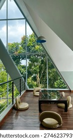This exquisite modern interior features striking triangular windows that frame a breathtaking vista of a dense tropical forest, creating a serene and open atmosphere perfect for relaxation and enjoying nature's beauty.