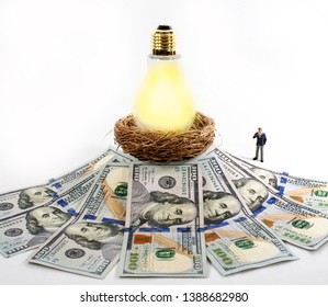 This Eye Catching Image Of A Miniature Businessman Thinking About Investment Ideas, Could Be Used For Wealth Management, Real Estate And Health Or Medical Financing. Nest Egg With Hundred Dollar Bills