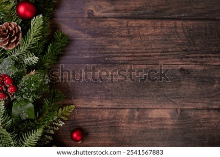 This eye-catching rustic Christmas background highlights a graceful layout of vivid red ornaments and fresh pine branches over a textured dark wood surface, perfect for festive design projects.