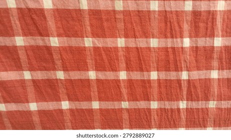 This fabric features a classic rust-orange and white checkered gingham pattern, woven with alternating colored squares that create a clean, timeless appearance. The lightweight cotton-like texture gives it a soft and breathable feel, making it suitable for clothing, table linens, curtains, quilting, and craft projects. Its warm earthy orange tones combined with crisp white checks provide a charming rustic and farmhouse-inspired aesthetic.