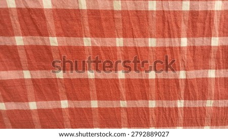 This fabric features a classic rust-orange and white checkered gingham pattern, woven with alternating colored squares that create a clean, timeless appearance. The lightweight cotton-like texture gives it a soft and breathable feel, making it suitable for clothing, table linens, curtains, quilting, and craft projects. Its warm earthy orange tones combined with crisp white checks provide a charming rustic and farmhouse-inspired aesthetic.