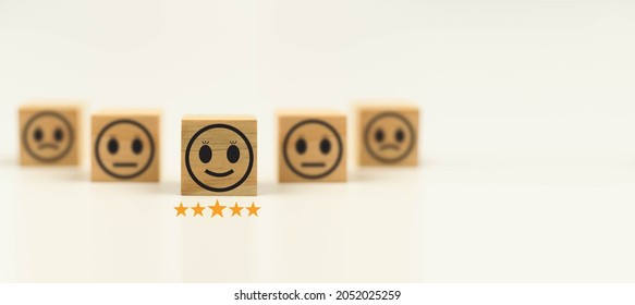This Feedback with smile face wood cube happy smiley face icon to give satisfaction in service. rating very impressed. Black, Customer service and Satisfaction concept. Copy space, Selective focus.