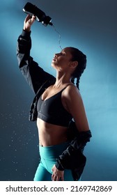 This Feels So Refreshing. Studio Shot Of A Sporty Young Woman Pouring Water On Her Face Against A Blue Background.