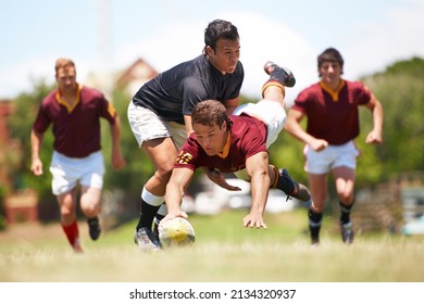 This Game Is Not For The Faint Hearted. Full Length Shot Of A Young Rugby Player Scoring A Try Mid Tackle.