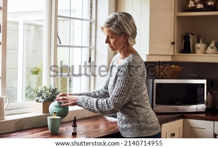 This is going to sort me out. Cropped shot of a relaxed senior woman preparing a cup of tea with CBD oil inside of it at home during the day.