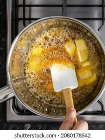 This Is A Hand Stirring The Caramel Added With Butter Using A Spatula In A Saucepan On The Stove