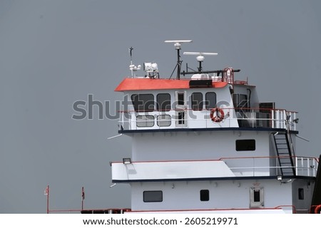 This high-resolution image captures the upper structure of a modern tugboat, highlighting the wheelhouse outfitted with cutting-edge marine radar, communication antennas, and navigation equipment. 