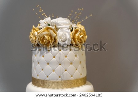 This high-resolution image features a three-tiered white wedding cake with gold trimming, perfect for adding a touch of elegance to special occasion